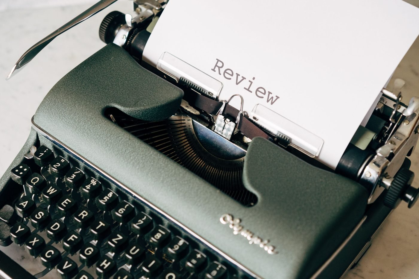 A vintage Olympia typewriter with a sheet of paper reading 'Review'